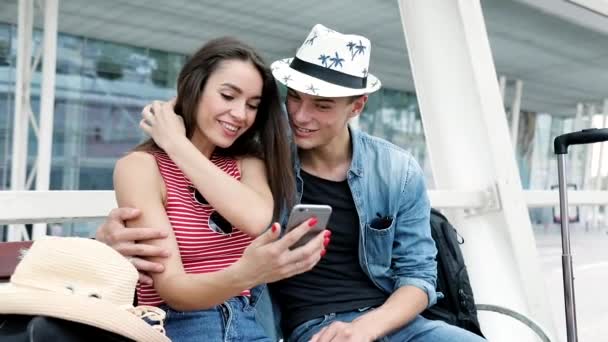 Viajar. casal usando telefone, esperando transporte perto do aeroporto — Vídeo de Stock