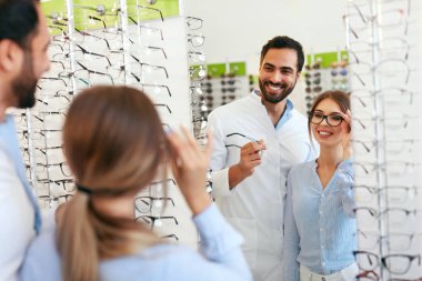 Kadın gözlük gözlük mağazasında, ayna yakınındaki gözlükteki çalışan erkek seçimi ile göz doktoru. Yüksek çözünürlük