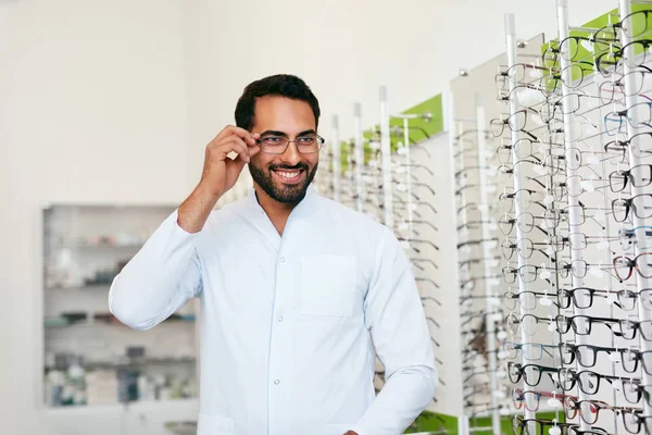 Optikermannen nær Showcase with Eyeglasses at Glasses Shop – stockfoto