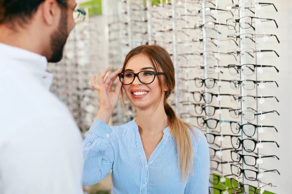 Optik-Geschäft. Augenarzt hilft Frau bei der Brillenwahl — Stockfoto