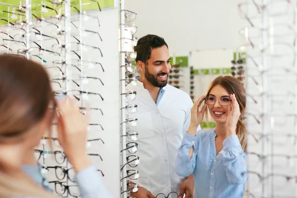 女性の眼鏡店で眼鏡を選択すると眼科医 — ストック写真