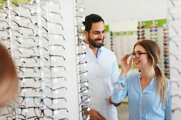 Médico de ojos con mujer eligiendo gafas en la tienda de gafas —  Fotos de Stock