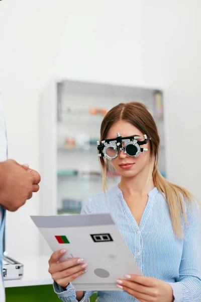 Examen oculaire. Femme dans les lunettes d'optométrie lisant la carte de test oculaire — Photo