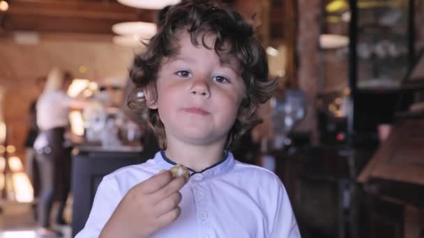 Lindo chico comer chocolate caramelo en confitería — Vídeos de Stock