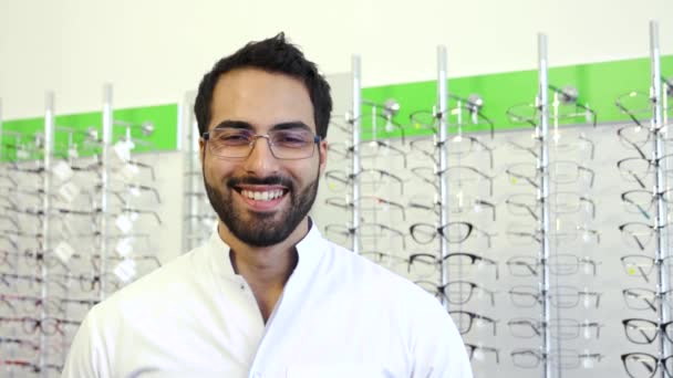 Médico óptico perto da mostra com óculos na loja de óculos — Vídeo de Stock