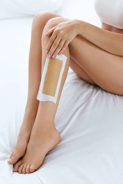 Uzun kadın bacaklar saç balmumu şerit Closeup ile. Epilasyon