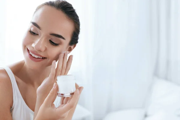 Cuidado de la piel de belleza. Hermosa mujer aplicando crema en la piel de la cara — Foto de Stock