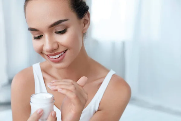 Cuidado de la piel de belleza. Hermosa mujer aplicando crema en la piel de la cara — Foto de Stock