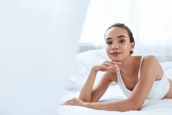 Belleza chica con hermosa cara y piel acostado en la cama blanca — Foto de Stock