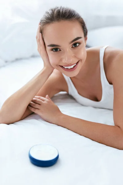 Face Skin Care. Mulher sorridente bonita com creme cosmético — Fotografia de Stock