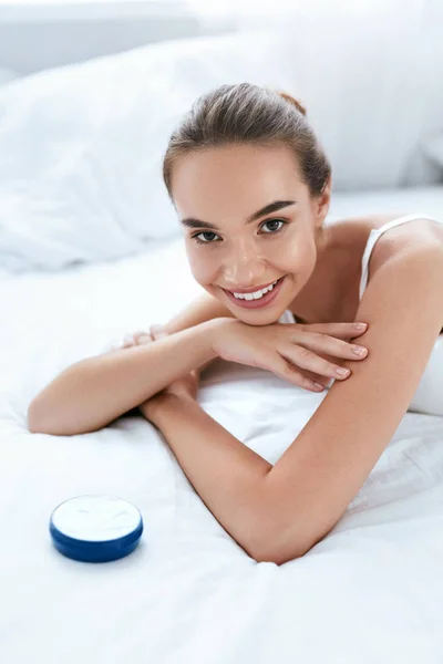 Cuidado de la piel facial. Bella mujer sonriente con crema cosmética —  Fotos de Stock