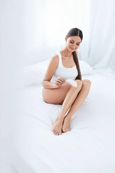 Pielęgnacja ciała. Kobiety dotykając skóry miękkie nogi gładkie z piór — Zdjęcie stockowe