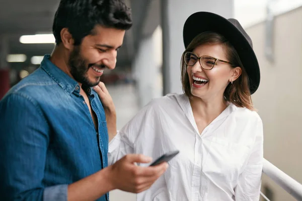 รูปภาพของคู่รักที่ยิ้มกับโทรศัพท์มือถือในร่ม — ภาพถ่ายสต็อก