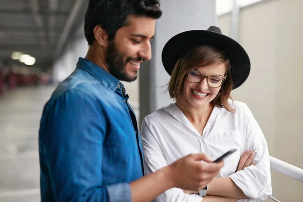 รูปภาพของคู่รักที่ยิ้มกับโทรศัพท์มือถือในร่ม — ภาพถ่ายสต็อก