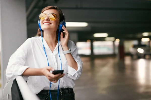 Fashion. Woman In Headphones With Phone Listening Music