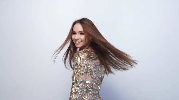 Modemädchen mit langen Haaren im goldenen Kleid hat Spaß beim Tanzen — Stockvideo