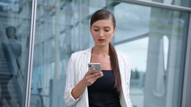 Mulher bonita com telefone andando perto do escritório de negócios — Vídeo de Stock