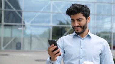 Yakışıklı adam sokakta iş merkezi yakınlarındaki telefon kullanarak