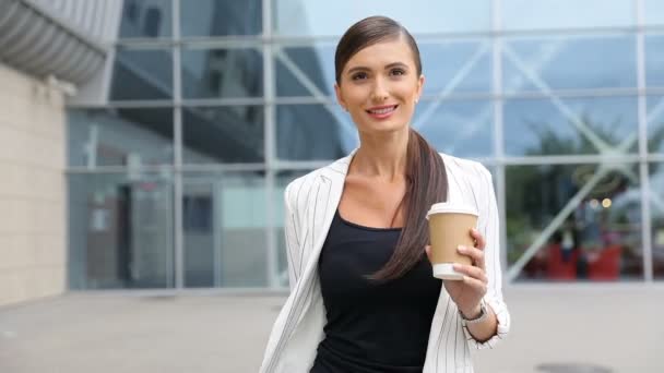 Деловая женщина с кофейником и чемоданом шагает по аэропорту — стоковое видео
