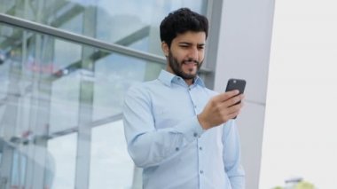 Sokakta iş merkezi yakınlarındaki telefon kullanan yakışıklı adam. Office Açık havada telefon ile gülümseyen iş adamı