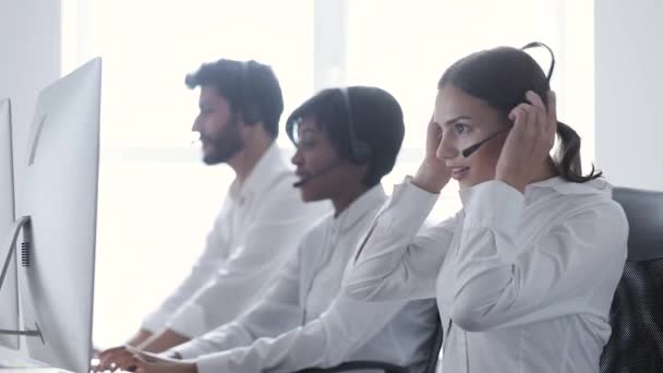 Centro de llamadas. Mujer sonriente en auriculares trabajando en la computadora — Vídeos de Stock