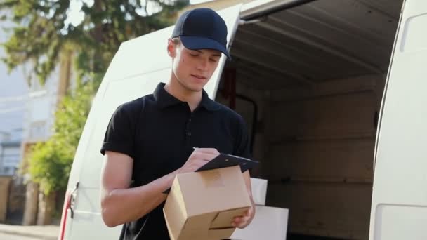 Servicio de entrega. Mensajero con caja en las manos cerca del coche al aire libre — Vídeo de stock