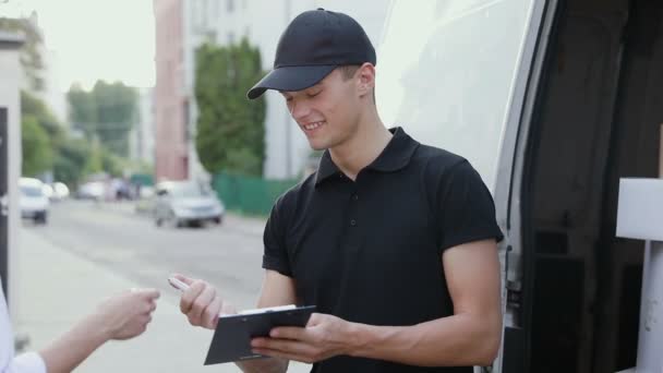 Servicio de mensajería. El hombre entrega el paquete a la mujer — Vídeos de Stock