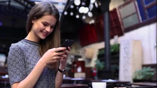 Женщина с телефоном в кафе пьет кофе — стоковое видео