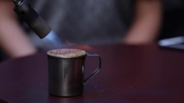 Kahve Cafe, Barista yapımı içki alev ateş etmek ile hizmet veren. Masada sıcak içecek fincanla