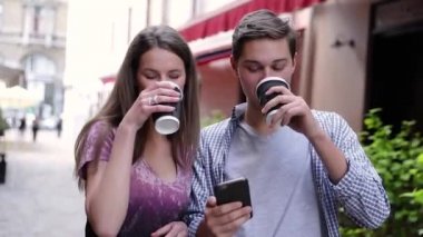 Cep telefonu kullaranarak ve açık havada kahve içme mutlu çift