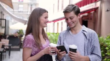 Cep telefonu kullaranarak ve açık havada kahve içme mutlu çift