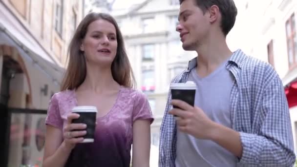 Νέοι άνθρωποι πίνουν καφέ και το περπάτημα στο δρόμο της πόλης — Αρχείο Βίντεο