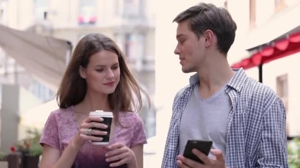 Pareja feliz usando el teléfono móvil y beber café al aire libre — Vídeos de Stock