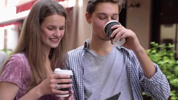 Gelukkige paar met behulp van de mobiele telefoon en koffie drinken buitenshuis — Stockvideo