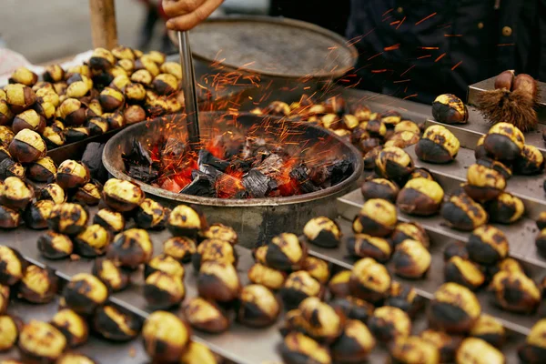 Mercado de comida callejera. Cocinar castañas asadas en primer plano de carbón — Foto de Stock