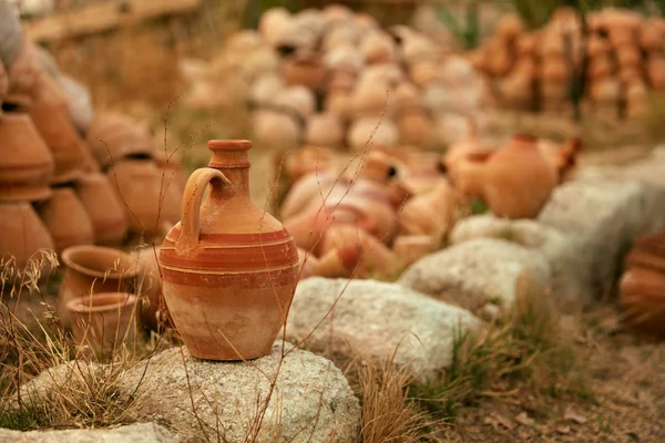 Clay kruik op steen met aardewerk potten op achtergrond — Stockfoto