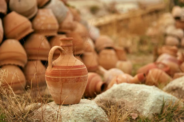 Πήλινη οινοχόη πάνω σε πέτρα με κεραμικά βάζα σε φόντο — Φωτογραφία Αρχείου