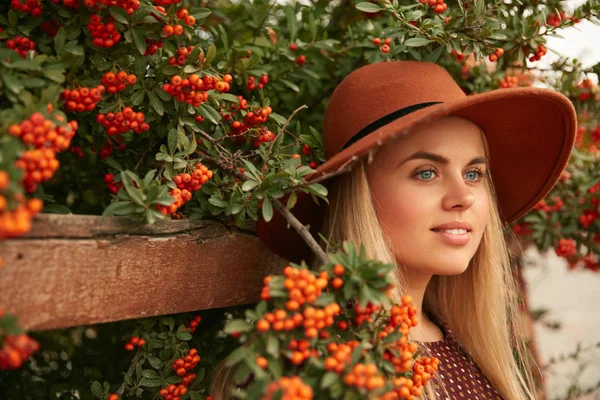 Retrato de mujer hermosa en sombrero cerca del árbol con bayas —  Fotos de Stock