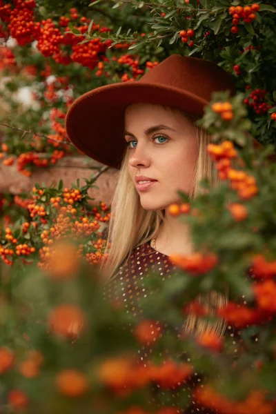 Ritratto di bella donna in cappello vicino albero con bacche — Foto Stock