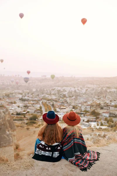 Pessoas viajam. Mulheres em chapéus na colina desfrutando de balões voadores — Fotografia de Stock