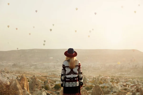 Viajar. hermosa mujer en sombrero viendo volar globos de aire caliente — Foto de Stock