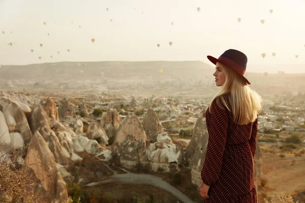 Viajar. hermosa mujer en sombrero con vuelo aire globos en el cielo — Foto de Stock