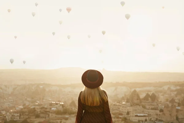 Viajar. hermosa mujer en sombrero con vuelo aire globos en el cielo — Foto de Stock