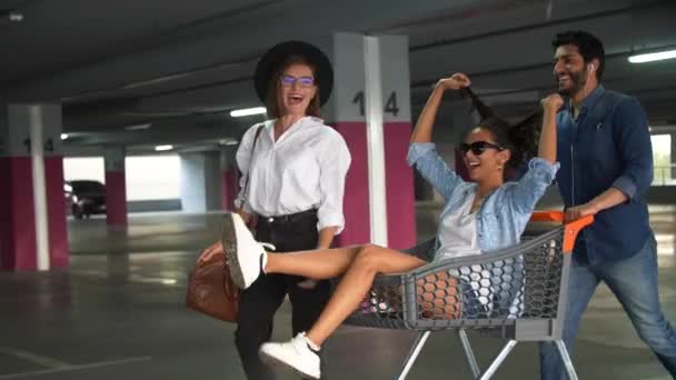Jugendliche haben Spaß, rasen auf Einkaufswagen auf Parkplatz — Stockvideo