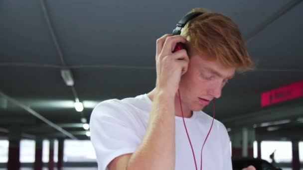 Hombre joven con auriculares escuchando música y usando el teléfono — Vídeo de stock