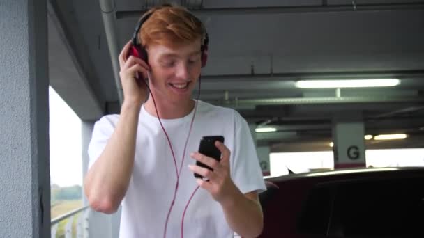 Hombre joven con auriculares escuchando música y usando el teléfono — Vídeos de Stock