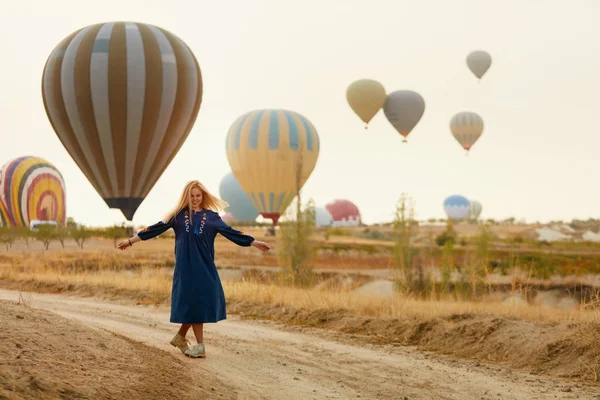 Mujer divirtiéndose con volar globos de aire caliente en el fondo —  Fotos de Stock