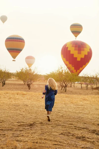 Kobieta działa w dziedzinie, gorące powietrze balony latające — Zdjęcie stockowe