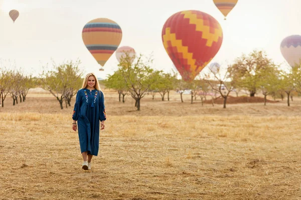 Mujer en el campo con globos de aire caliente volando en Bakcground —  Fotos de Stock