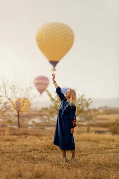 Mujer hermosa tratando de alcanzar globo de aire caliente en el cielo con la mano —  Fotos de Stock